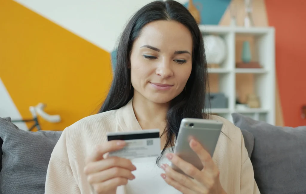 Person using phone and credit card.